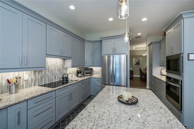 kitchen with decorative light fixtures, light stone counters, appliances with stainless steel finishes, and tasteful backsplash