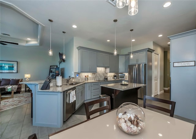 kitchen with pendant lighting, a breakfast bar area, light stone counters, kitchen peninsula, and stainless steel appliances