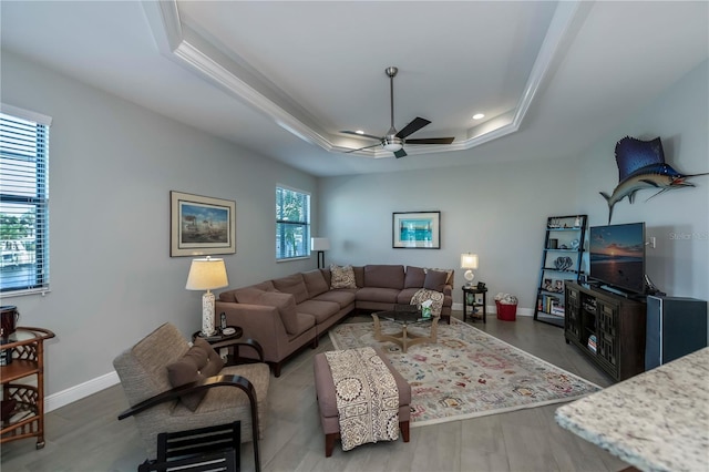 living room featuring hardwood / wood-style flooring, ceiling fan, a healthy amount of sunlight, and a tray ceiling