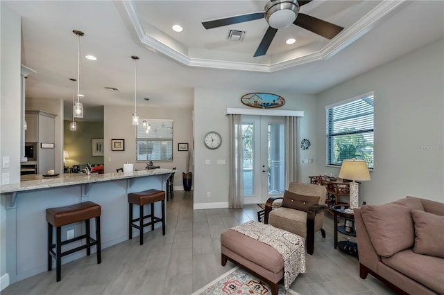 living room featuring a tray ceiling, ceiling fan, and ornamental molding