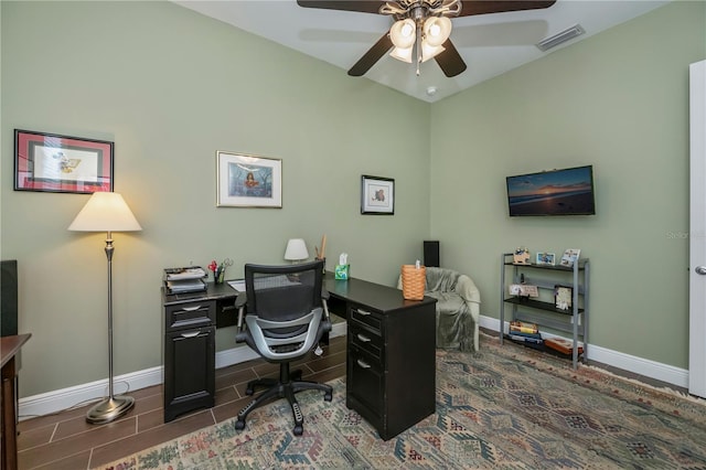 home office with dark tile patterned floors and ceiling fan