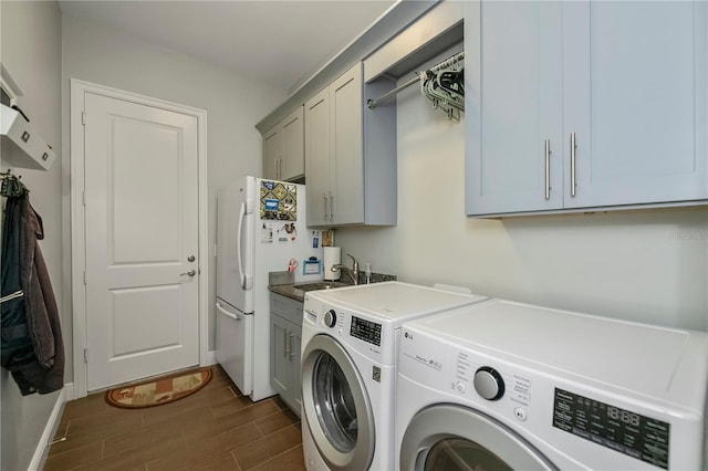 laundry room with cabinets, sink, dark hardwood / wood-style floors, and washing machine and clothes dryer