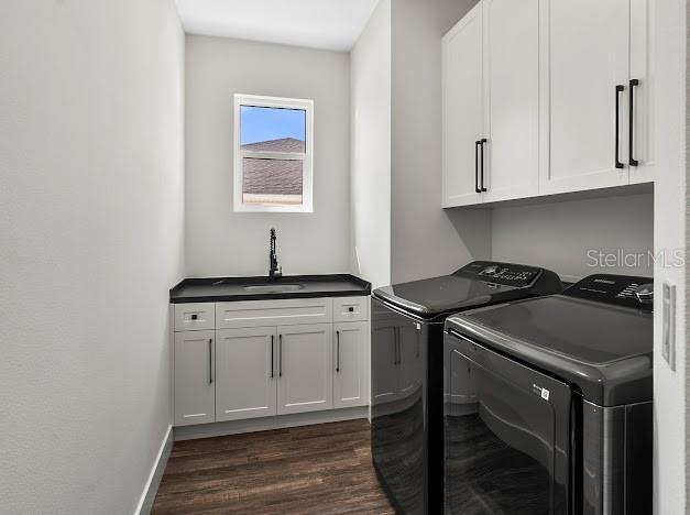 clothes washing area with dark hardwood / wood-style flooring, cabinets, sink, and washer and dryer