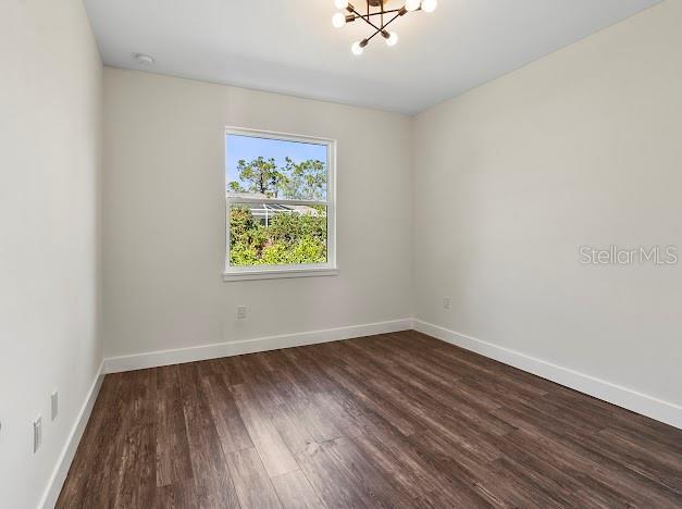 spare room with dark hardwood / wood-style flooring and a notable chandelier