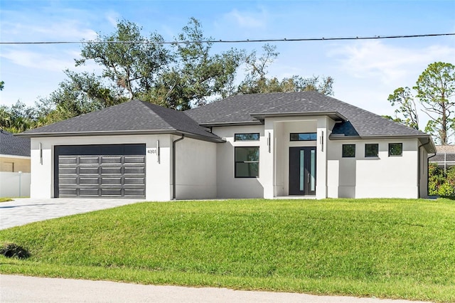 prairie-style house with a garage, driveway, a front yard, and stucco siding