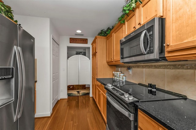 kitchen with decorative backsplash, light wood-type flooring, stainless steel appliances, and dark stone counters