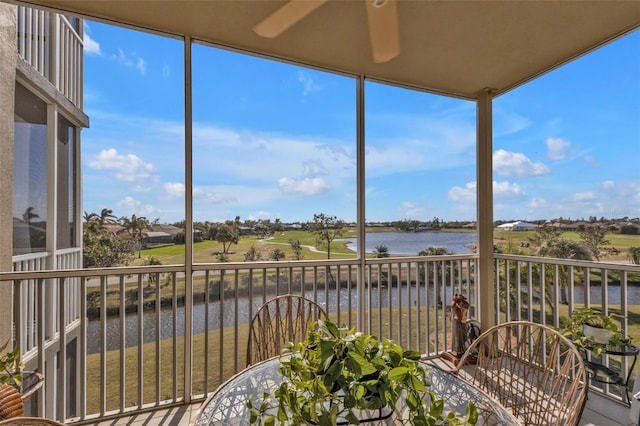 sunroom / solarium with ceiling fan and a water view