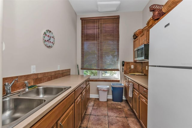 kitchen featuring decorative backsplash, white fridge, and sink