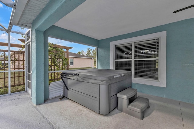 view of patio with a hot tub and glass enclosure