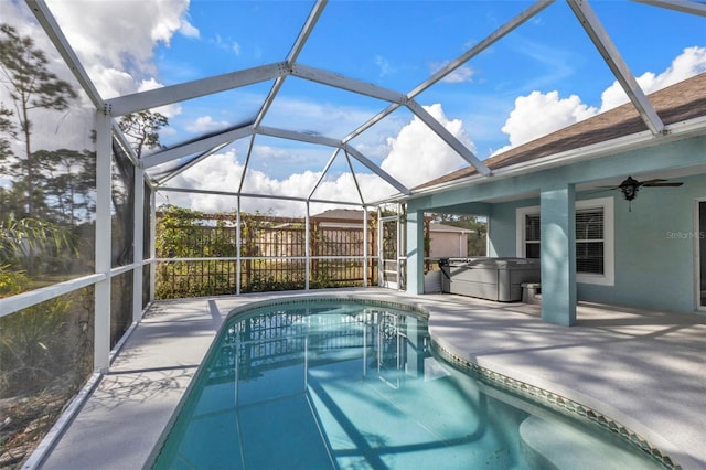 view of pool with a hot tub, glass enclosure, ceiling fan, and a patio area