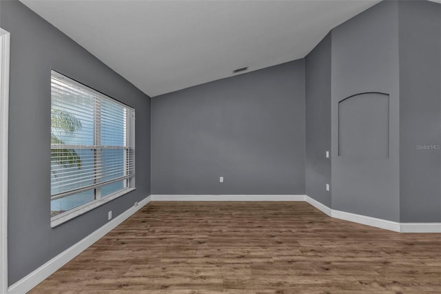 unfurnished room with hardwood / wood-style flooring and vaulted ceiling