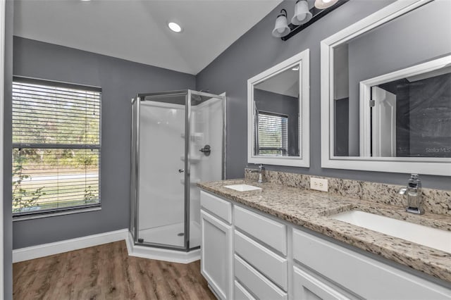 bathroom with lofted ceiling, plenty of natural light, a shower with door, and vanity