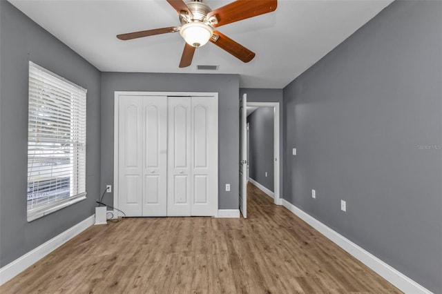 unfurnished bedroom with light wood-type flooring, ceiling fan, and a closet