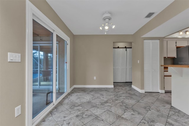 unfurnished dining area with a barn door and an inviting chandelier