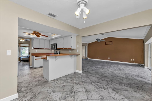 kitchen featuring wooden counters, white cabinets, vaulted ceiling, appliances with stainless steel finishes, and kitchen peninsula