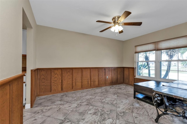 unfurnished office with ceiling fan and wood walls