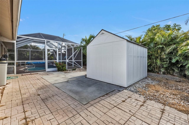 view of patio featuring glass enclosure and a storage unit