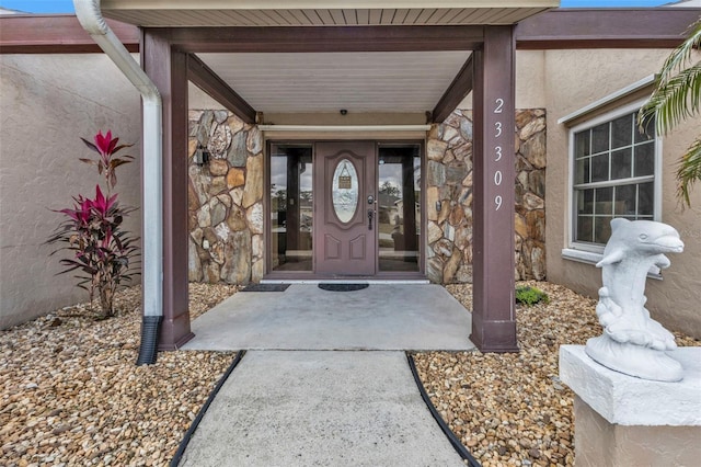 property entrance with stucco siding and stone siding