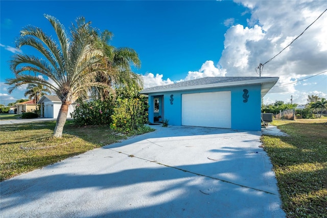 view of front of home featuring a front yard, an outbuilding, a garage, and cooling unit