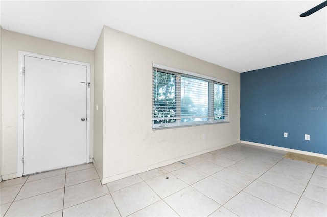 tiled spare room with ceiling fan