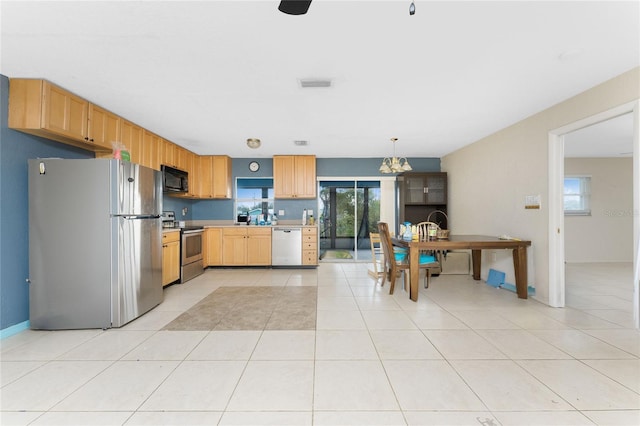 kitchen with stainless steel appliances, a chandelier, pendant lighting, light brown cabinetry, and light tile patterned floors