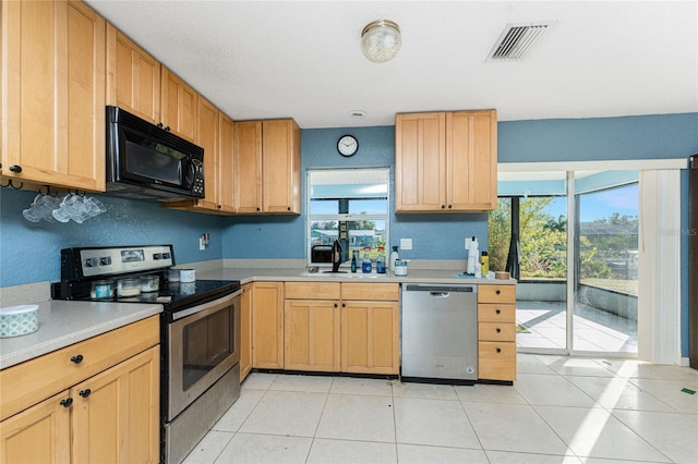 kitchen featuring a wealth of natural light, light tile patterned floors, sink, and appliances with stainless steel finishes