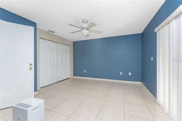 unfurnished bedroom with ceiling fan, a closet, and light tile patterned flooring