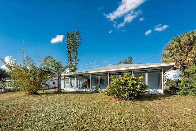 rear view of house featuring a lawn and a sunroom