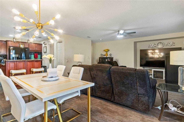 dining area featuring ceiling fan with notable chandelier and dark hardwood / wood-style flooring