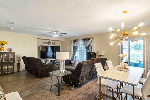 living room with a textured ceiling, ceiling fan with notable chandelier, plenty of natural light, and dark wood-type flooring