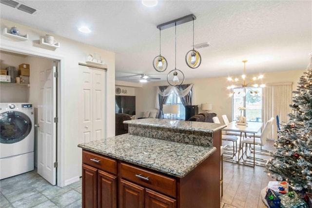 kitchen with ceiling fan with notable chandelier, decorative light fixtures, light hardwood / wood-style flooring, a center island, and washer / clothes dryer