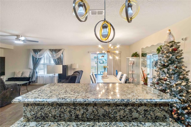 dining space featuring a textured ceiling, hardwood / wood-style floors, and ceiling fan with notable chandelier