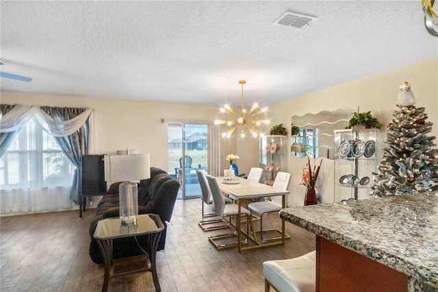 dining room with a textured ceiling, dark hardwood / wood-style floors, and an inviting chandelier