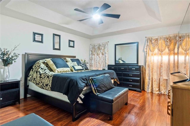 bedroom featuring a raised ceiling, ceiling fan, and dark wood-type flooring