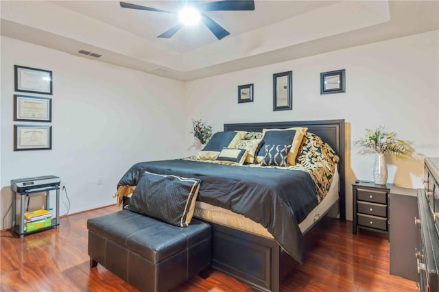 bedroom featuring a tray ceiling, ceiling fan, and dark hardwood / wood-style flooring