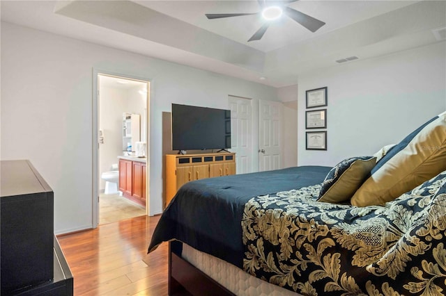 bedroom with ceiling fan, light hardwood / wood-style floors, and ensuite bath