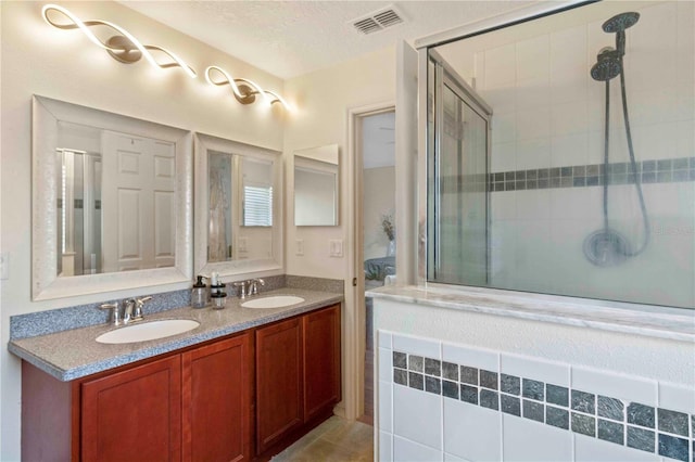 bathroom with tile patterned floors, vanity, a textured ceiling, and walk in shower