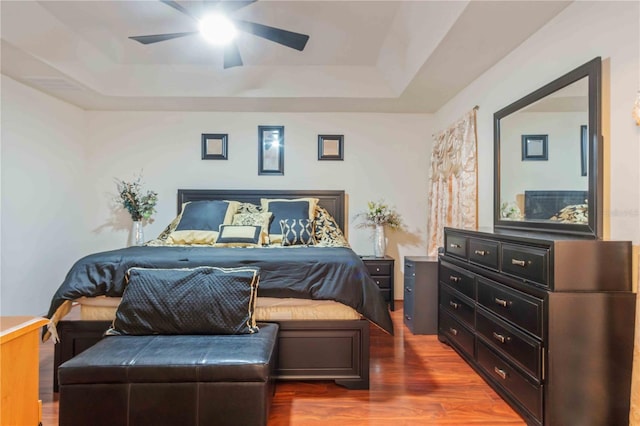 bedroom featuring dark hardwood / wood-style flooring, a tray ceiling, and ceiling fan