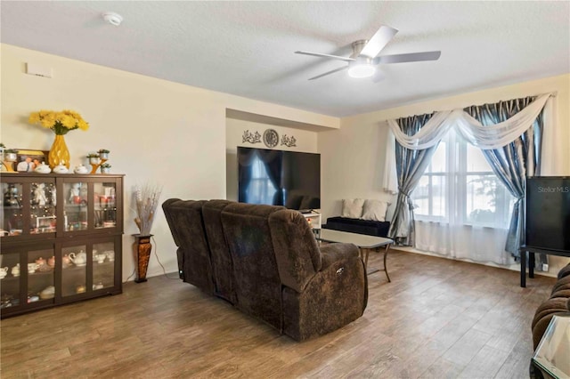 living room with ceiling fan, hardwood / wood-style floors, and a textured ceiling