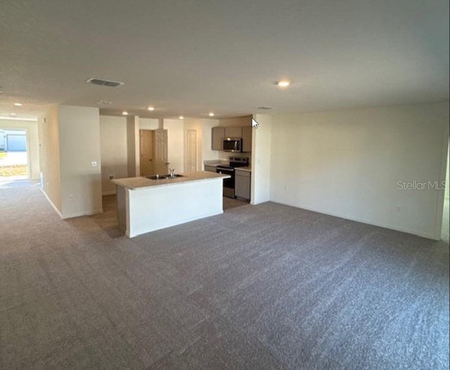 kitchen featuring appliances with stainless steel finishes, light colored carpet, a kitchen island with sink, sink, and gray cabinets