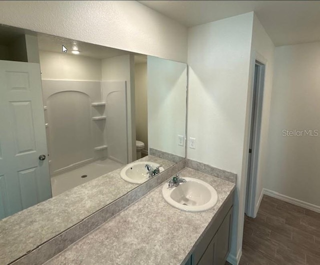 bathroom featuring walk in shower, vanity, and toilet