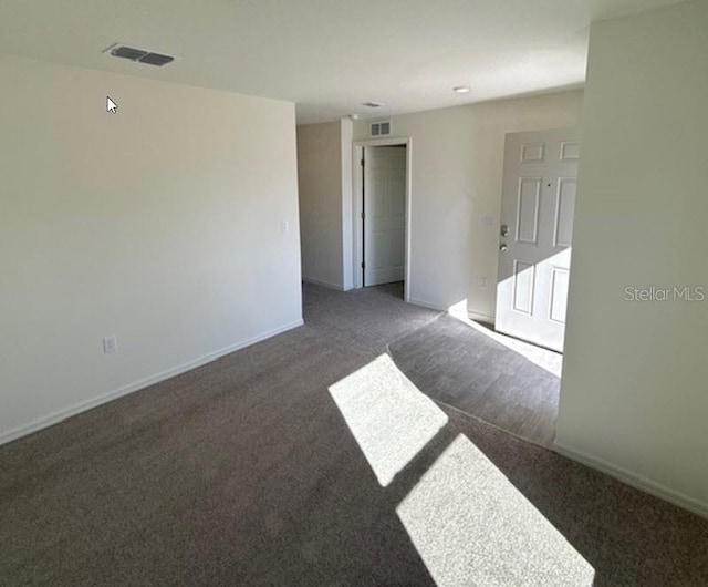 spare room with dark colored carpet