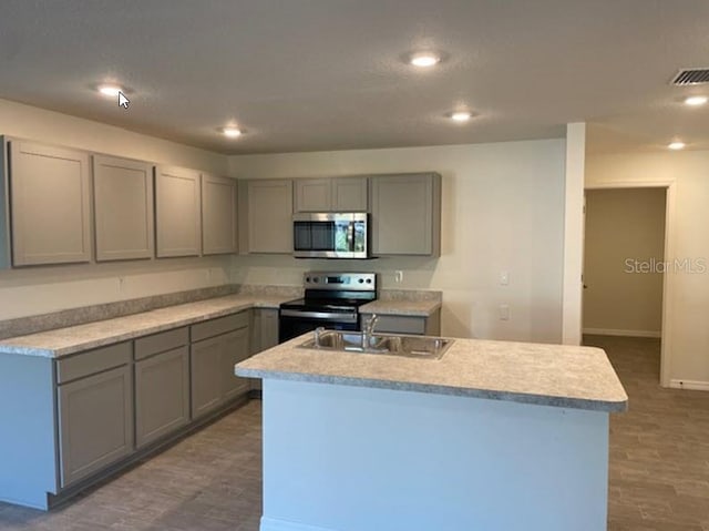 kitchen with a center island with sink, gray cabinetry, and appliances with stainless steel finishes