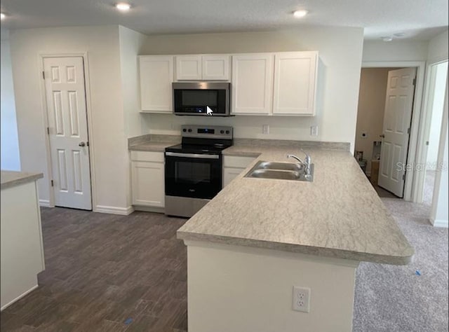 kitchen with kitchen peninsula, appliances with stainless steel finishes, dark wood-type flooring, sink, and white cabinetry