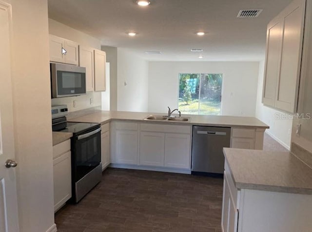 kitchen with kitchen peninsula, sink, white cabinets, and appliances with stainless steel finishes