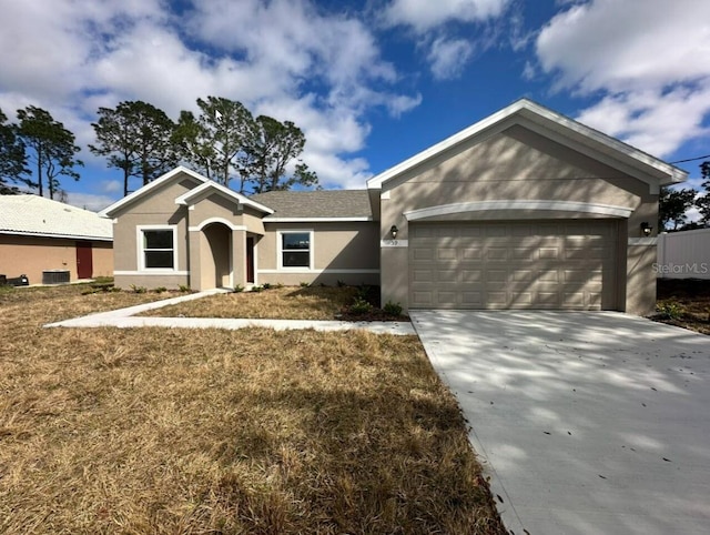 single story home featuring a garage, a front yard, concrete driveway, and stucco siding