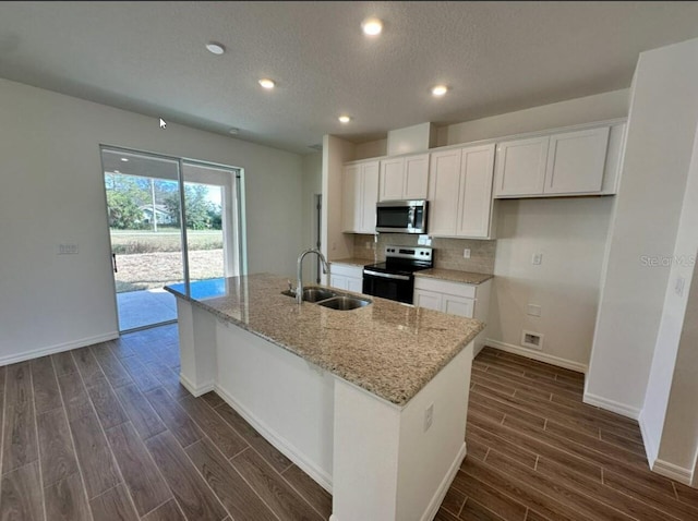 kitchen featuring electric range, stainless steel microwave, a sink, and a kitchen island with sink