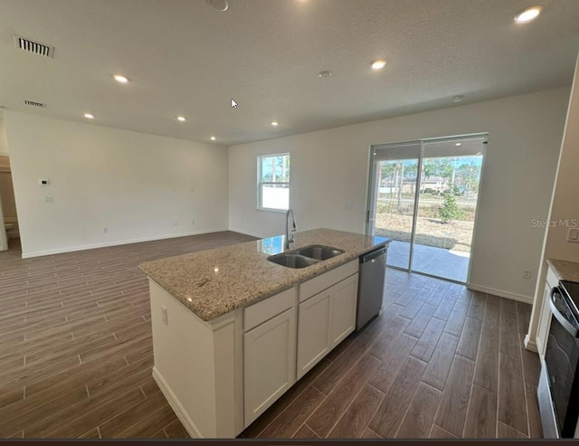 kitchen featuring a center island with sink, electric range oven, stainless steel dishwasher, white cabinetry, and a sink