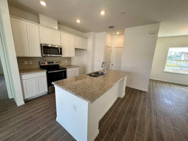 kitchen with visible vents, appliances with stainless steel finishes, white cabinets, a sink, and an island with sink