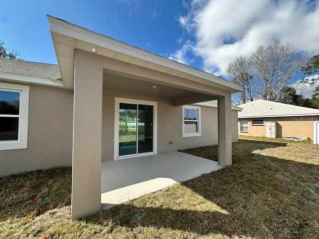 back of house featuring a patio area, a shingled roof, a lawn, and stucco siding